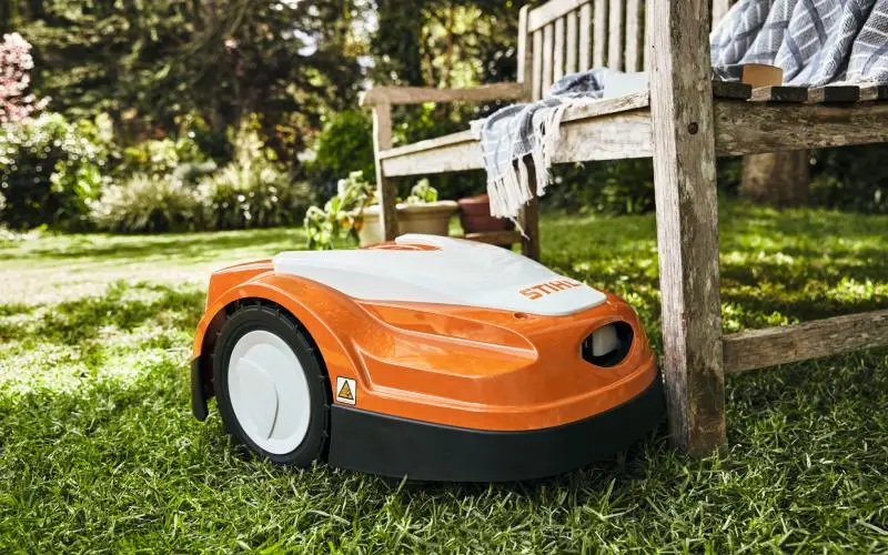 Ρομποτικό χλοοκοπτικό STIHL κόβει το γκαζόν δίπλα σε ξύλινο παγκάκι – Κατηγορία Περιποίηση Γκαζόν